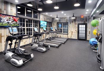 A gym with treadmills and weights and a tv
